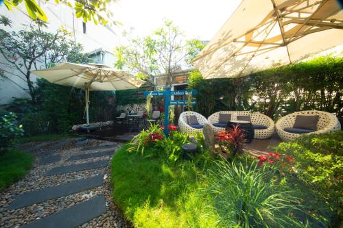 a garden with a patio with chairs and an umbrella at Alagon Saigon Hotel & Spa in Ho Chi Minh City