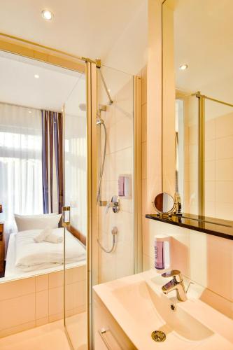 a bathroom with a shower and a sink and a mirror at Hotel am Fischerstrand in Bansin