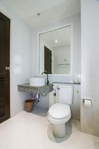a white bathroom with a toilet and a sink at Natural Beach Hotel Pattaya in Pattaya