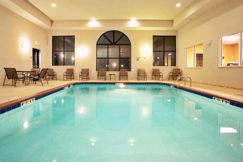 ein großer Pool in einem Hotel mit Stühlen und Tischen in der Unterkunft Holiday Inn Express Hotel & Suites Claypool Hill -Richlands Area, an IHG Hotel in Pounding Mill