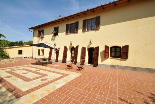 a building with chairs and a patio in front of it at Agriturismo Mannaioni in Volterra