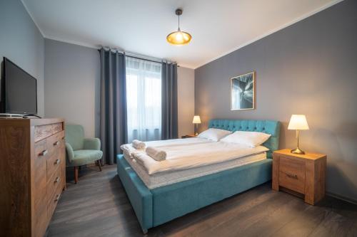 ViewMountain - Apartamenty Cieplice في يلينيا غورا: غرفة نوم بسرير ازرق وتلفزيون