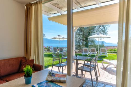 ein Wohnzimmer mit einem Sofa, einem Tisch und Stühlen in der Unterkunft La Chioma di Berenice Garda Residence in Toscolano-Maderno