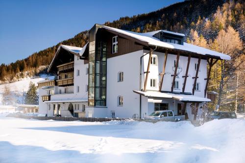 duży budynek w śniegu przed górą w obiekcie Valluga Hotel w mieście Sankt Anton am Arlberg