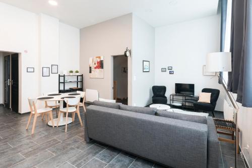a living room with a couch and a table and chairs at Au détour des Places in Arras