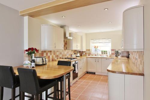 a kitchen with white cabinets and a wooden table at Goose's Getaway in Wells next the Sea