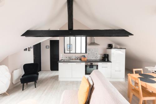 a kitchen with white cabinets and a black chandelier at Au détour des Places in Arras