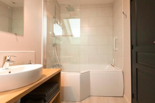a white bathroom with a sink and a tub at Au détour des Places in Arras