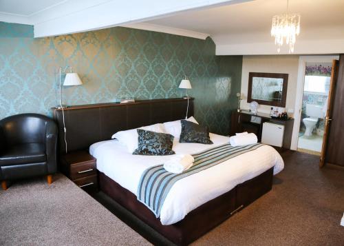 a bedroom with a bed and a chair and a mirror at Avarest House Bed and Breakfast in Portrush