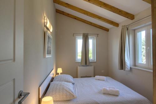 a bedroom with a bed and two windows at Complex of 2 villas Mugeba III with 2 private pools for up to 16 persons in Porec near the Aquapark in Mugeba