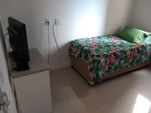 a small bedroom with a bed and a tv at Apto em santos 900 m praia in Santos