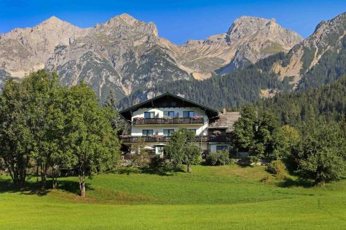 a house in a field with mountains in the background at Sonnenhügel in Ramsau am Dachstein