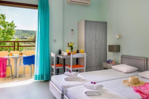 a room with two beds and a balcony at Louladakis Apartments in Kolymvari