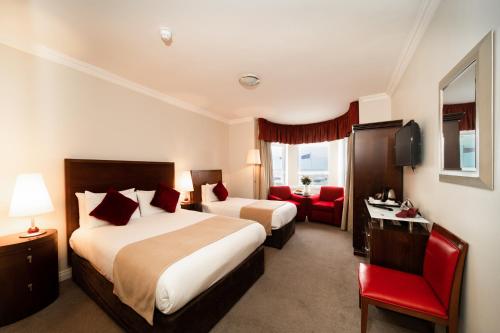 a hotel room with two beds and a red chair at White Sands Hotel in Portmarnock