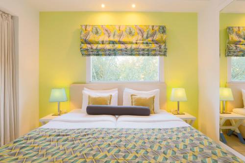 a bedroom with a large bed and two windows at Mandraki Village Boutique Hotel in Koukounaries