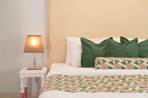 a bed with green pillows and a lamp on a table at Mandraki Village Boutique Hotel in Koukounaries