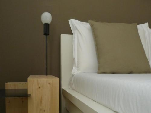 a bedroom with a bed with white sheets and a lamp at New Fontana Rooms in Como