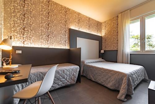 ラヴェンナにあるホテル アストリアのベッド2台とデスクが備わるホテルルームです。