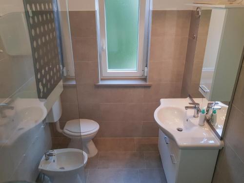 a bathroom with a sink and a toilet and a window at Apartments Lori in Poreč