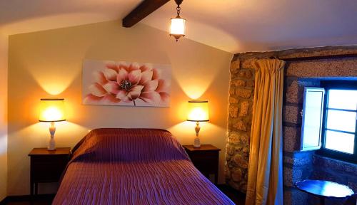 a bedroom with a bed and two lamps and a window at CASA DO CASTELLO MONSANTO in Monsanto
