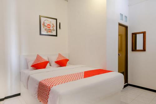 1 cama blanca con almohadas rojas en una habitación en OYO 1376 Kina Family Residence Syariah, en Malang