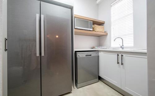 a stainless steel refrigerator in a kitchen with a sink at Driftwood by The Oyster Collection in Kenton on Sea