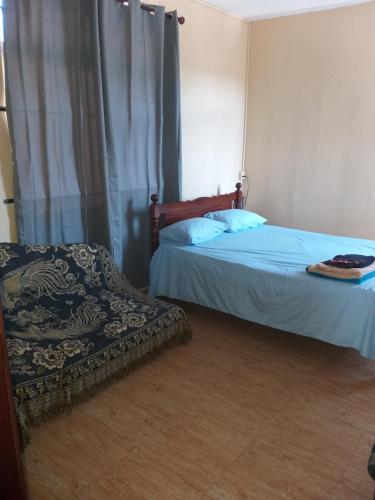 ein Schlafzimmer mit einem Bett, einem Stuhl und einem Fenster in der Unterkunft Maison Au Clos de La Forêt in Curepipe