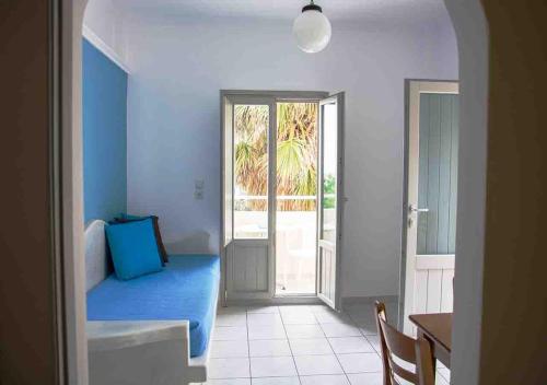 Zimmer mit einem blauen Bett, einem Tisch und einer Tür in der Unterkunft Sail Inn Studios & Apartments in Kamari