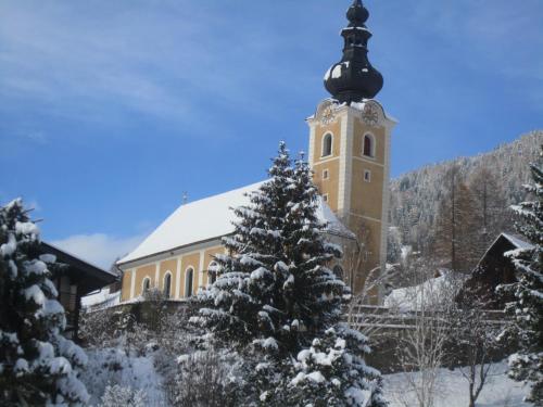 a building with a clock tower with a snow covered tree at Appartement Else in Bad Kleinkirchheim