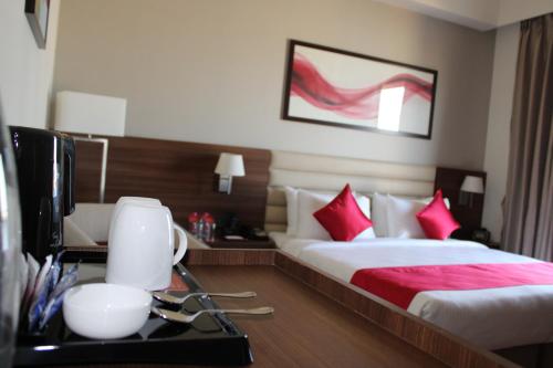 a hotel room with a bed and a desk with a tv at Ramada by Wyndham Gandhidham Shinay in Gandhidham