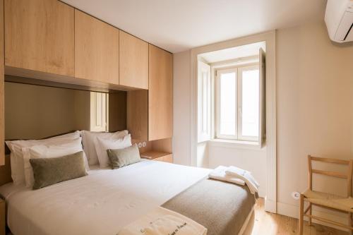 a bedroom with a large white bed with a window at Casas na Portuguesa - Bica Chiado in Lisbon