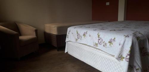 a bedroom with a bed and a chair next to a bedskirtspectspectspects at Residencial Franca Garopaba in Garopaba
