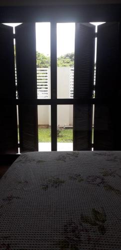 a room with a bed and a large window at Residencial Franca Garopaba in Garopaba