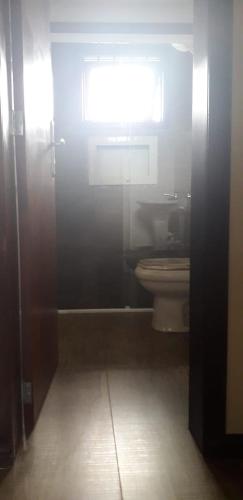 a bathroom stall with a toilet and a window at Residencial Franca Garopaba in Garopaba