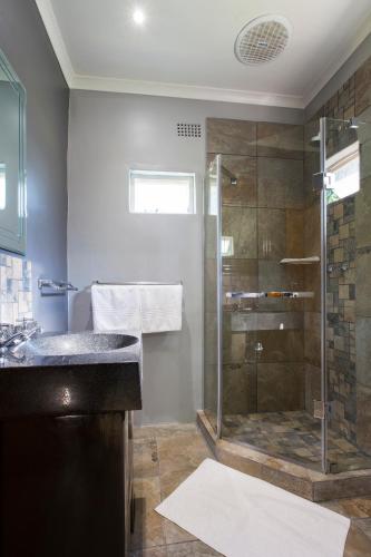 a bathroom with a glass shower and a sink at Merry Pebbles Resort in Sabie