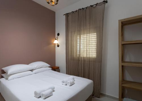 Un dormitorio con una cama blanca con toallas. en Modern 2BR with MAMAD by HolyGuest en Tel Aviv