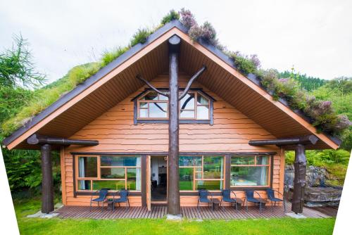 eine Blockhütte mit einem Grasdach und Stühlen in der Unterkunft Troll Fjordhytter in Syvde