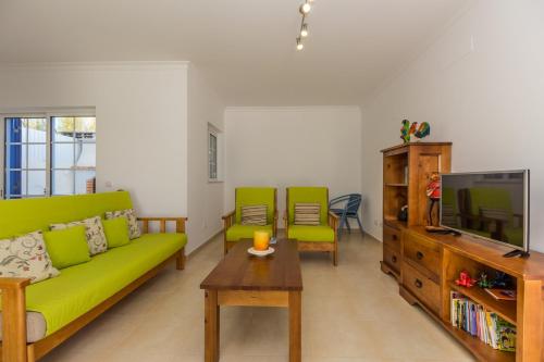 sala de estar con sofá verde y TV en Blue Villa by ALGARVEMANTA, en Manta Rota
