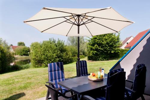 a table and chairs with an umbrella in a tent at Hebrechthuis in Vlagtwedde