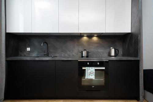una cucina nera con armadi bianchi e forno di Warsaw Prince Studio by Renters a Varsavia