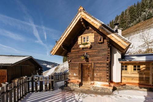 a log cabin in the snow with a fence at Bergappartements Pröll in Kleinarl