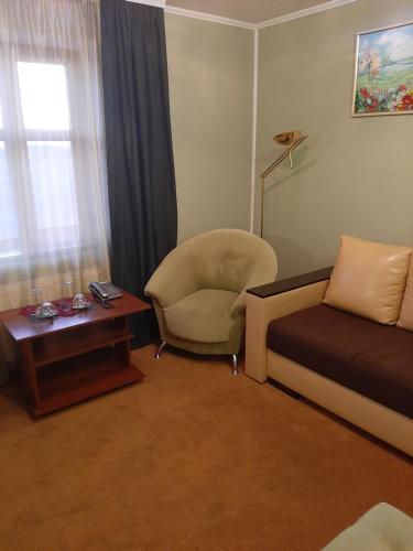 a living room with a bed and a chair and a table at Stara Vezha Hotel in Boryspilʼ