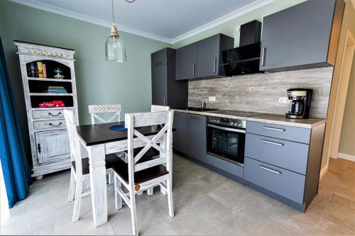 a kitchen with blue cabinets and a table and chairs at Ferienwohnung Freya in Gelbensande