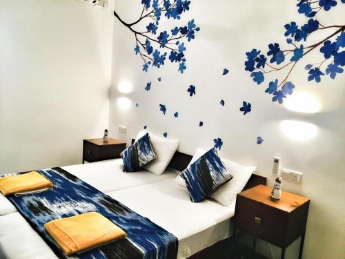 1 dormitorio con 1 cama con flores azules en la pared en Visakha 6, en Colombo