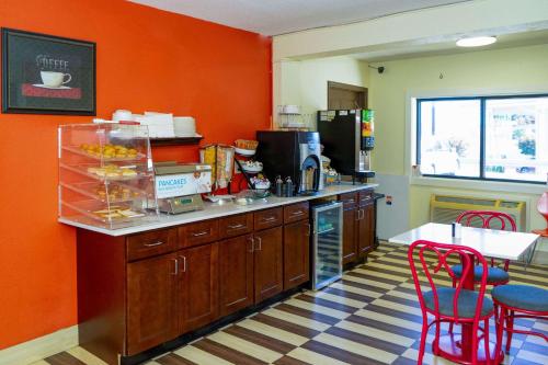 a kitchen with orange walls and a counter with red chairs at Econo Lodge Weldon - Roanoke Rapids in Weldon