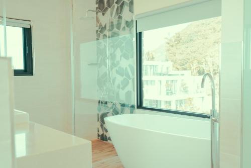 a white bathroom with a tub and a window at Shark B&B in Hengchun