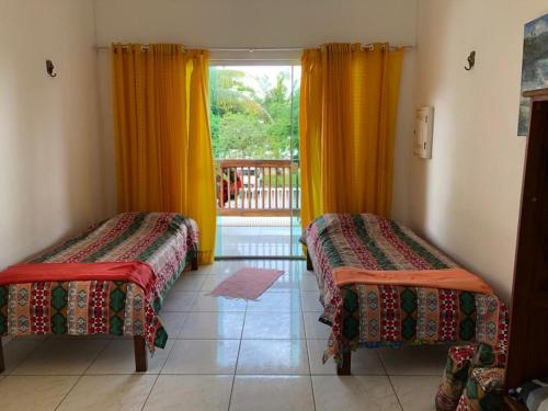 two beds in a room with yellow curtains at Flats Paraty in Paraty