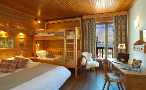 a bedroom with a bed and a desk with a laptop at Hôtel L'Arbina in Tignes