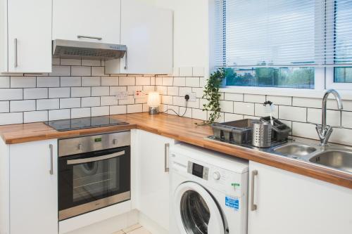 uma cozinha com uma máquina de lavar roupa e um lavatório em MyCityHaven The KingsWeston - flexible home sleeps 7 em Bristol