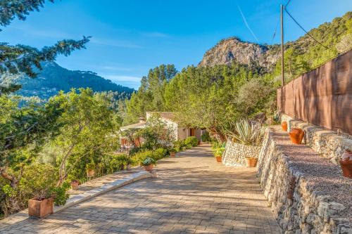 a stone wall with a pathway with plants and trees at Miravall in Puigpunyent